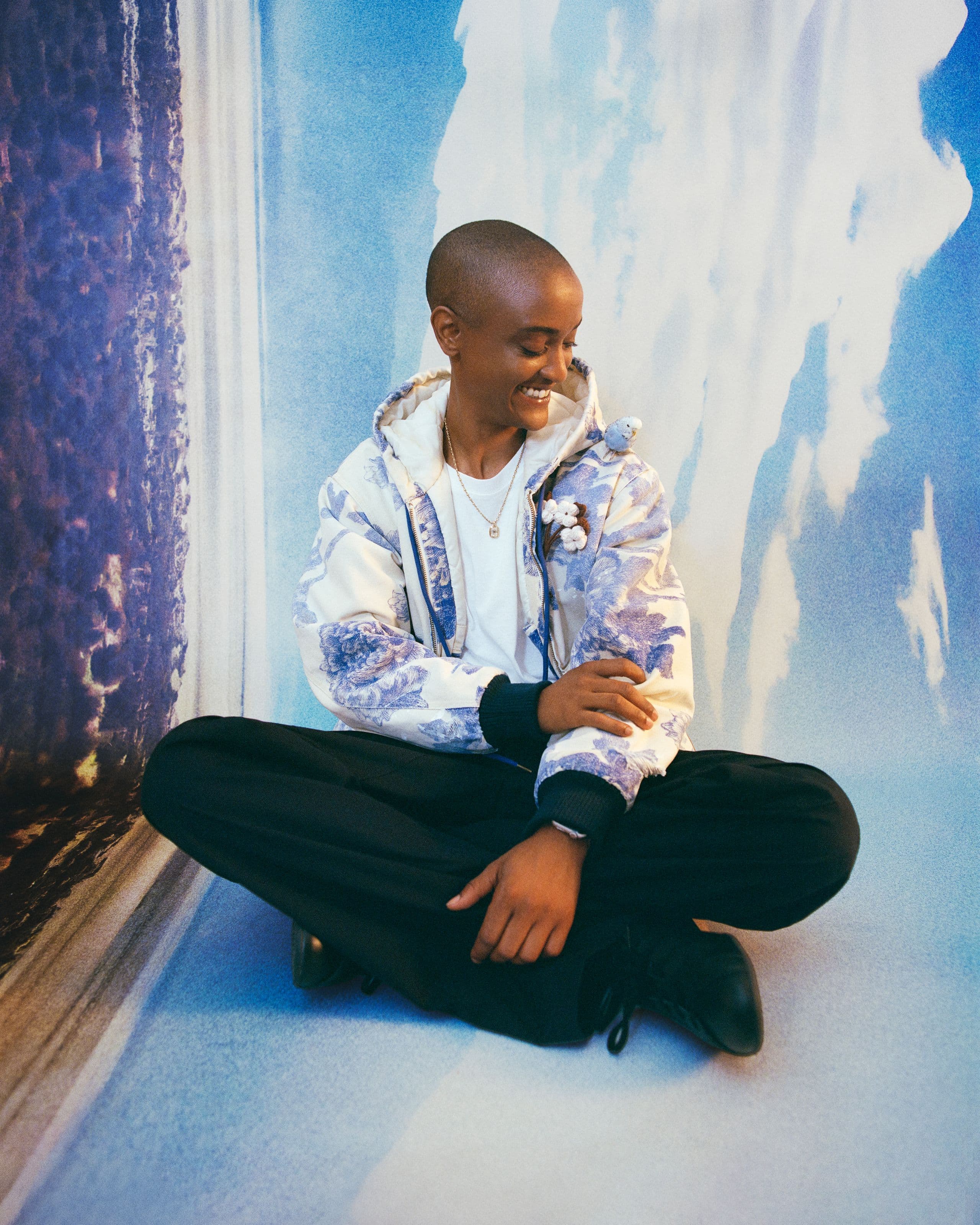 Syd sitting against a painted sky backdrop