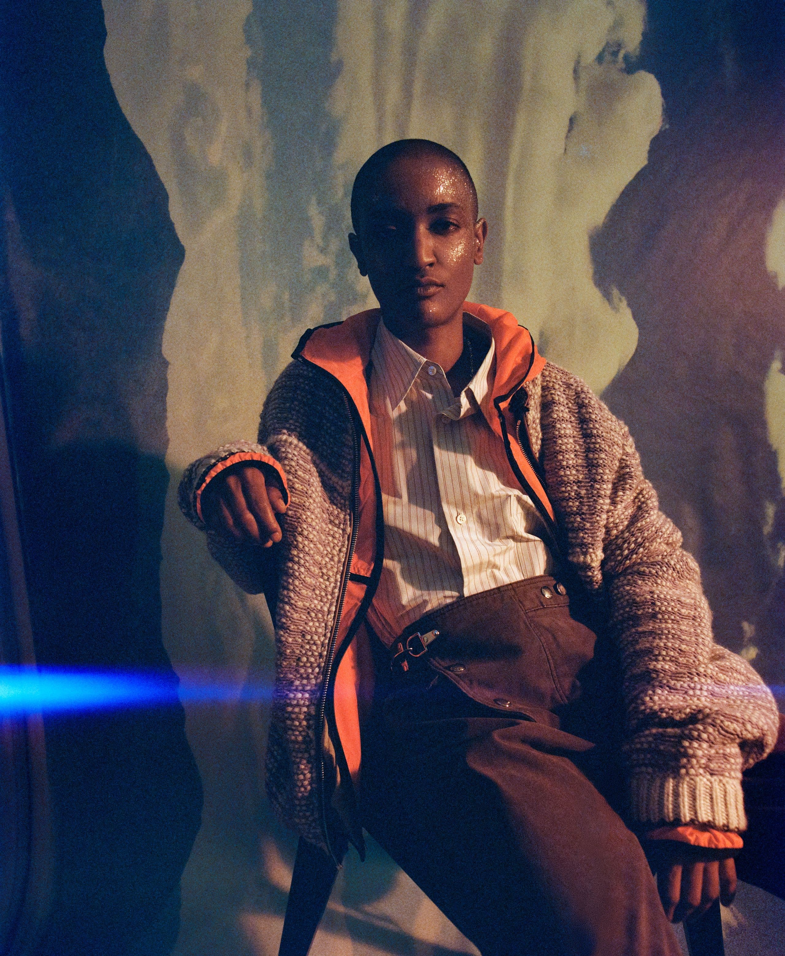 Syd seated in a knit cardigan